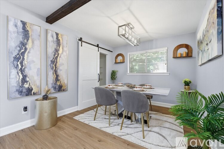 A dining room with a table set for four and a painting on the wall.