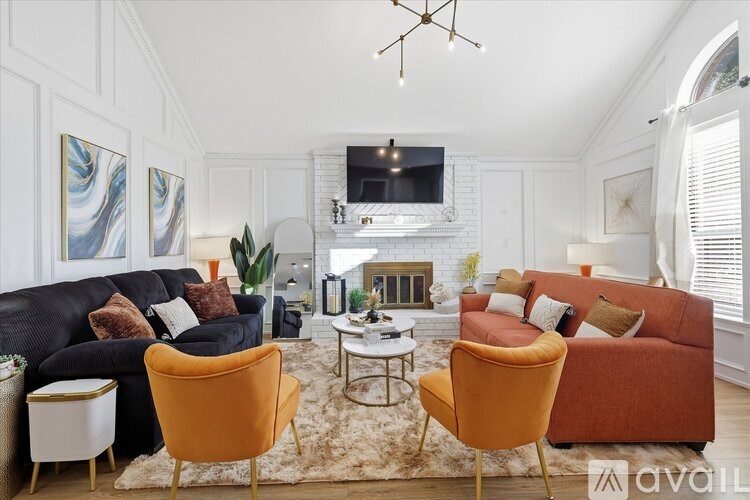 A living room with a black couch, orange armchair, and a white coffee table.
