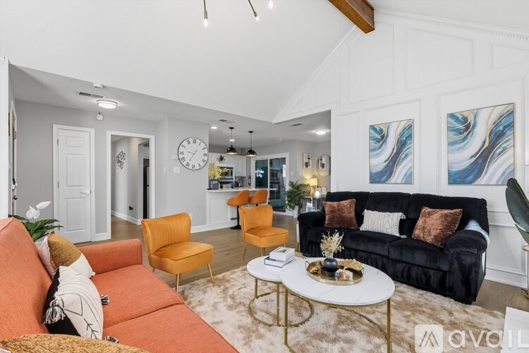 A living room with a black couch, orange couch, and a white coffee table.