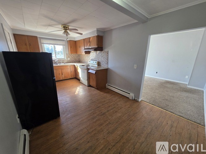 A kitchen with wooden floors and a black refrigerator.