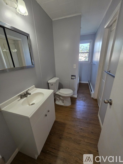 A bathroom with a sink, toilet and mirror.