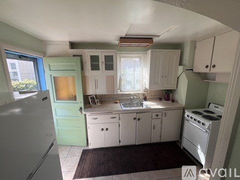 A kitchen with white cabinets and a green door.