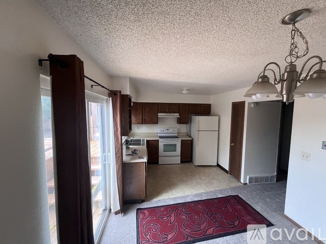 A kitchen with white appliances and a red rug on the floor.