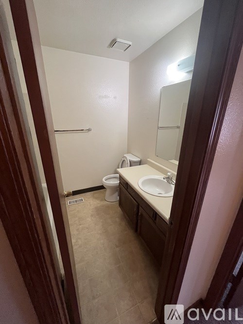 A bathroom with a toilet, sink, and mirror.