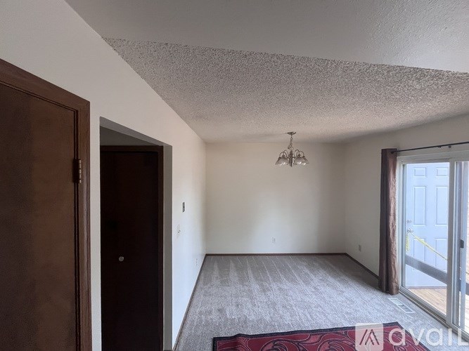 A room with a rug on the floor and a chandelier hanging from the ceiling.