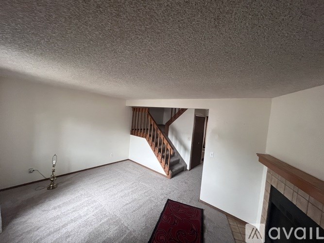 A room with a carpet and a fireplace.