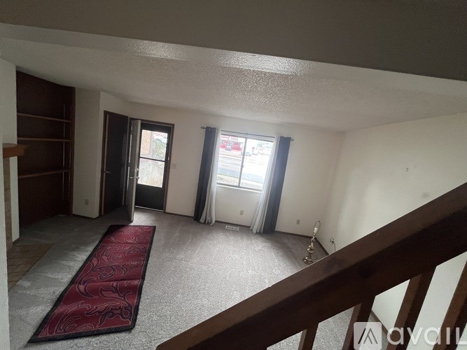 A room with a red runner on the floor leading to a door.