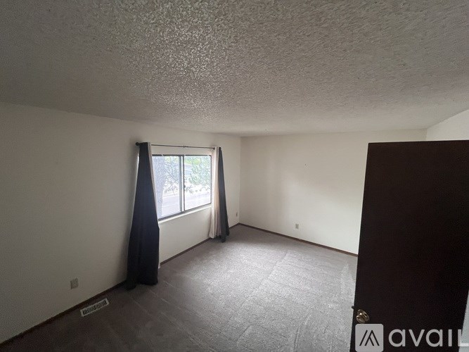 A room with a window and curtains is available for rent.