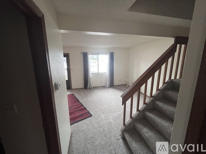 A hallway with a staircase and a red rug.