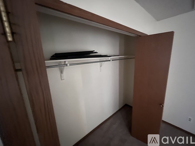 A small, empty closet with a brown door and a white wall.