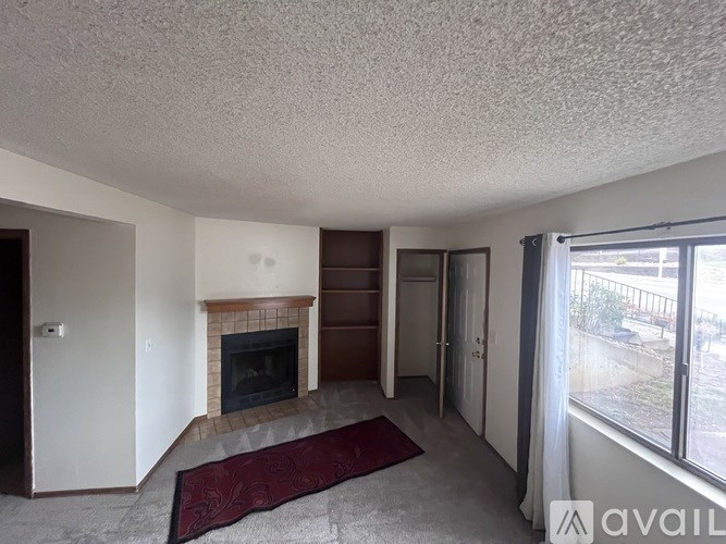 A living room with a fireplace and a rug on the floor.