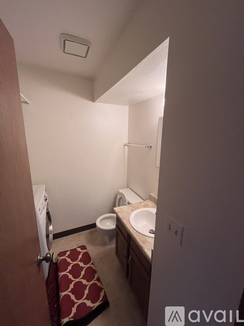 A bathroom with a toilet, sink, and washing machine.