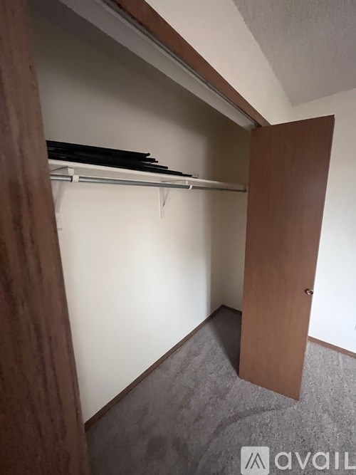 A small, empty room with a wooden door and a white wall.