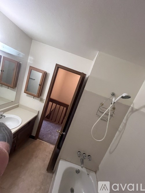 A bathroom with a tub, sink, mirror and shower.