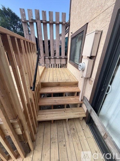 A wooden deck with a staircase leading to a balcony.