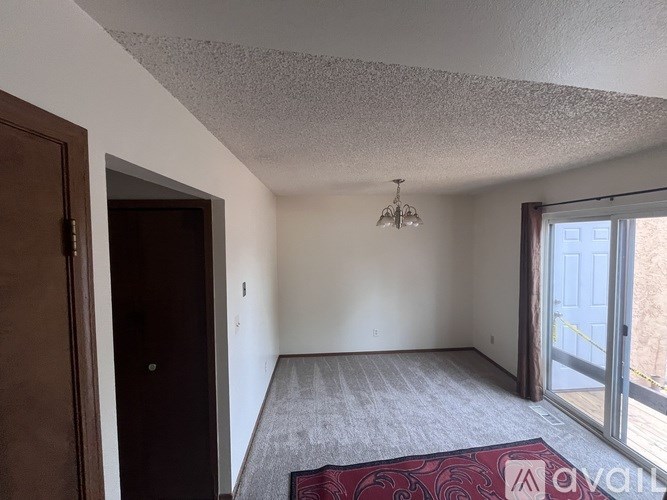 A room with a rug on the floor and a door on the left side.