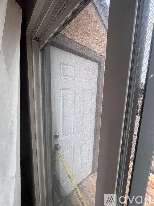 A white door with a yellow tape measure is seen through a glass door.