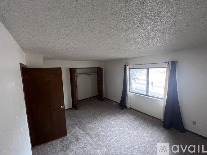 A room with a brown door and a window with blue curtains.