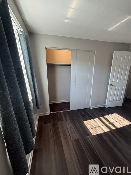 A room with a white door and a window with a curtain.