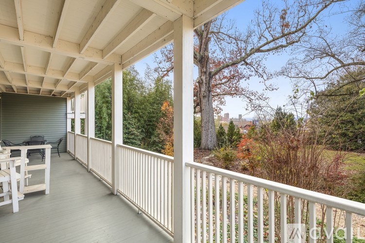 A white deck with a table and chairs overlooking a forest.