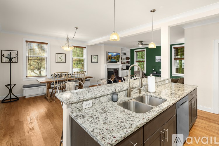 A kitchen with granite countertops and a dining area with chairs.