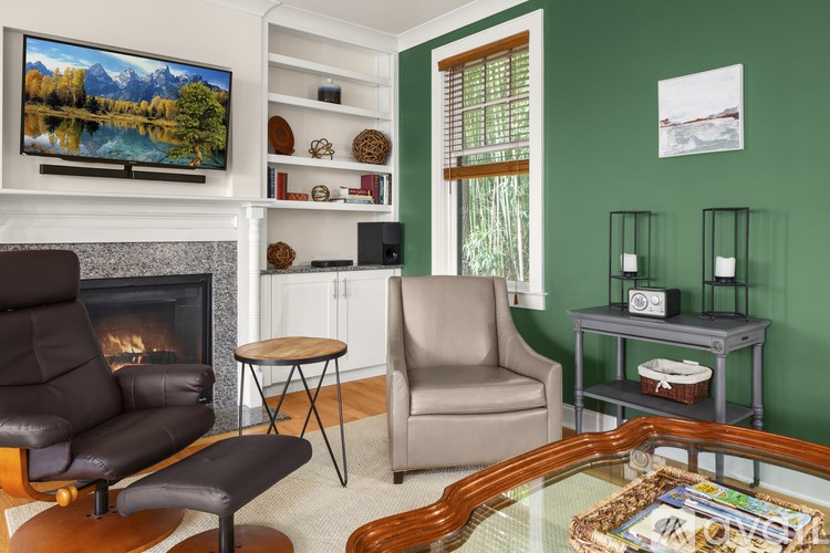 A living room with a fireplace, two chairs, a table, and a television.