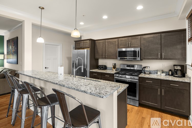 A kitchen with a marble countertop and dark brown cabinets.