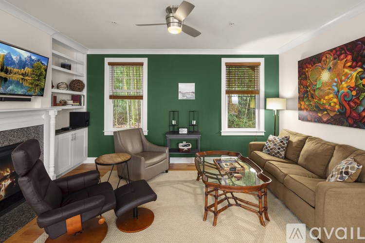 A living room with a fireplace, two chairs, a sofa, and a painting on the wall.