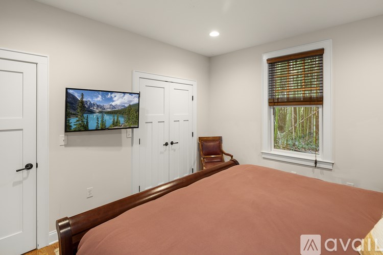 A bedroom with a large bed and a television mounted on the wall.
