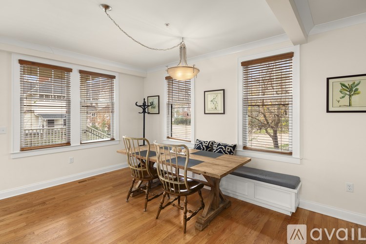 A dining room with wooden floors and a bench under a window.