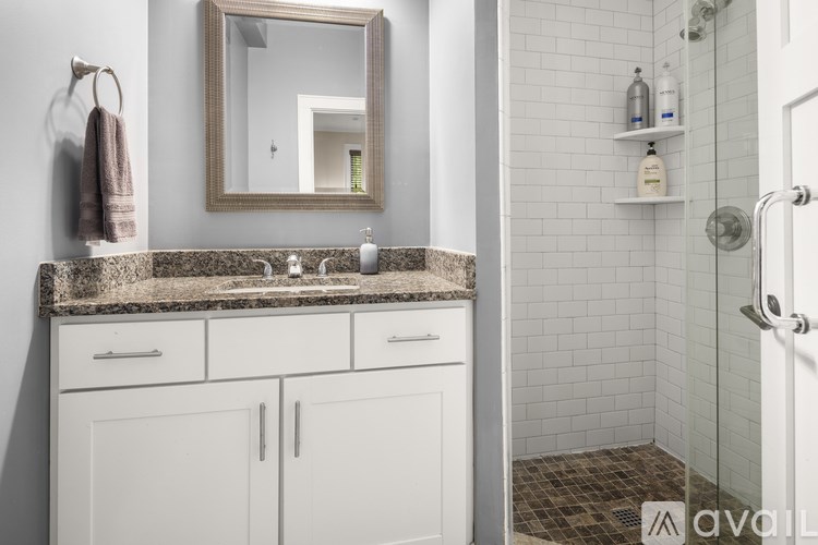 A bathroom with a marble countertop and white cabinets.