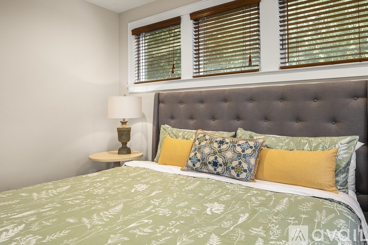 A bed with a green patterned sheet and four pillows.