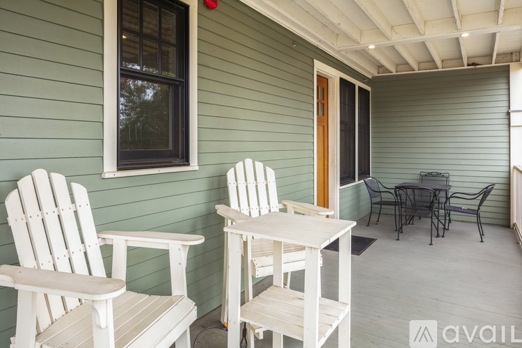 Two white chairs and a table are on a porch.