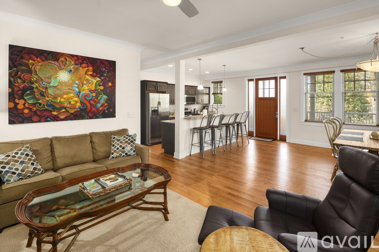 A living room with a brown couch and a painting on the wall.
