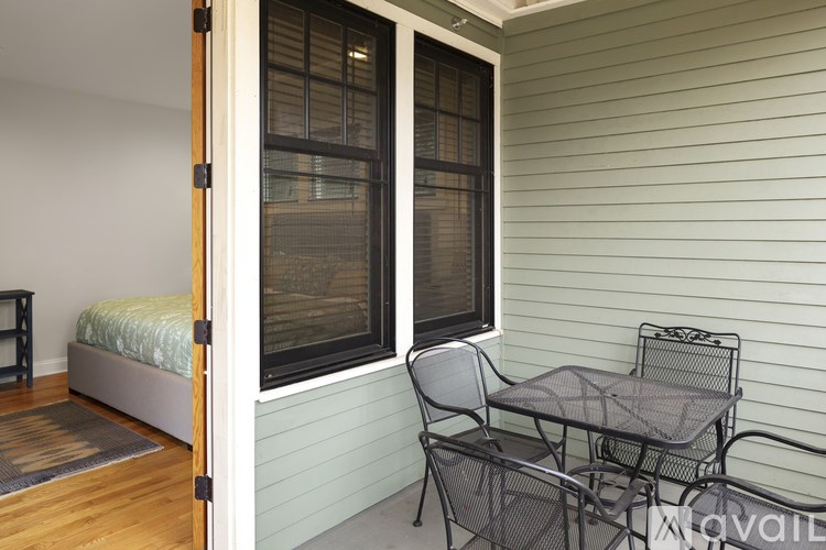 A small balcony with a bed, chair, and table.