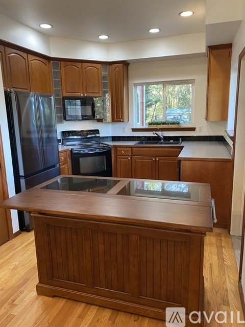 A kitchen with wooden cabinets and a black stove top oven.