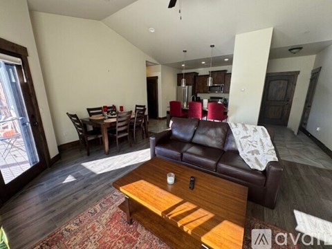 A living room with a brown leather couch and a wooden coffee table.