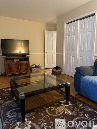 A living room with a glass coffee table and a television on a wooden stand.