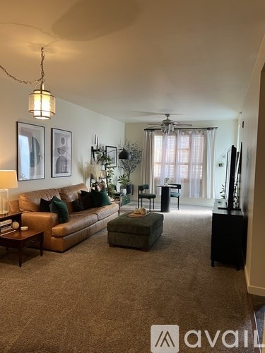 A living room with a brown couch and a green ottoman.