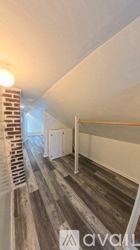 A hallway with a brick wall on the left and a white door on the right.