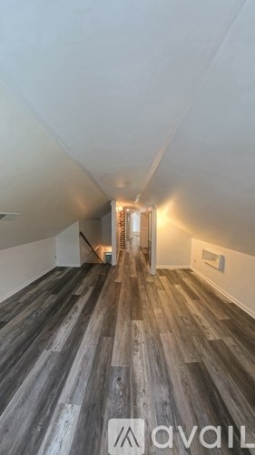 A hallway with wood flooring and white walls.