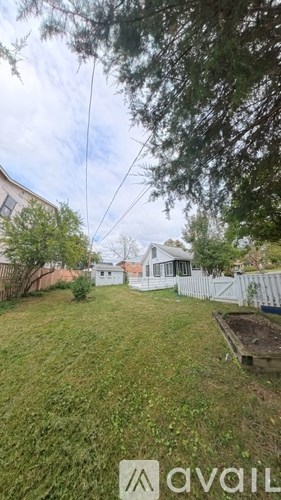 A backyard with a white fence and a small garden.