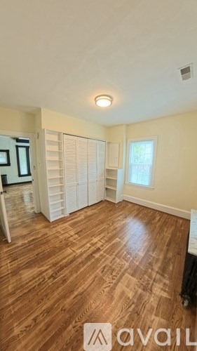 A room with wooden flooring and a window with blinds.
