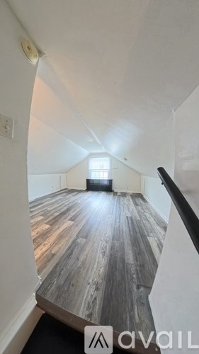A room with wooden flooring and a window in the distance.