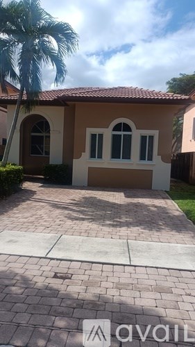 A house with a red tile roof and a palm tree in front.