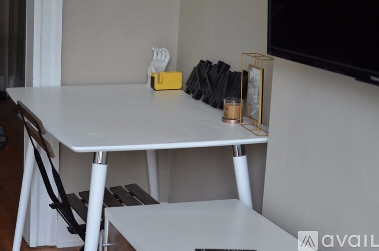 A white dining table with a yellow box and a candle on it.