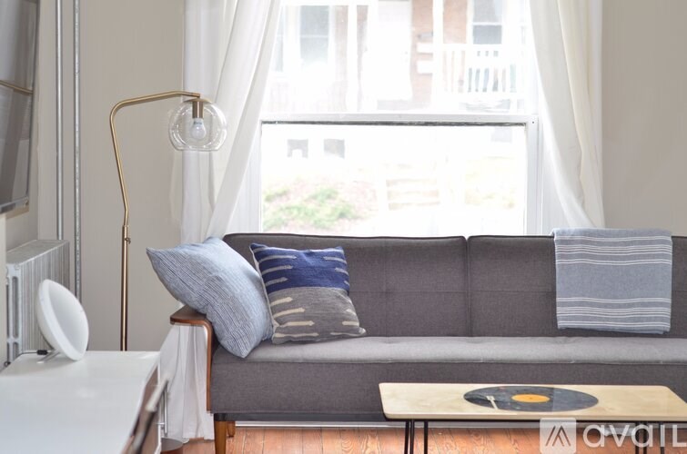 A grey couch with a white table in front of it.
