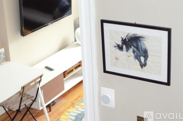 A painting of a black and white cat is hanging on a wall.