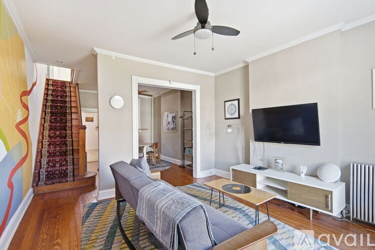 A grey couch with a blue pillow and a record player on a coffee table.