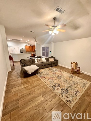 A living room with a rug and a fan.